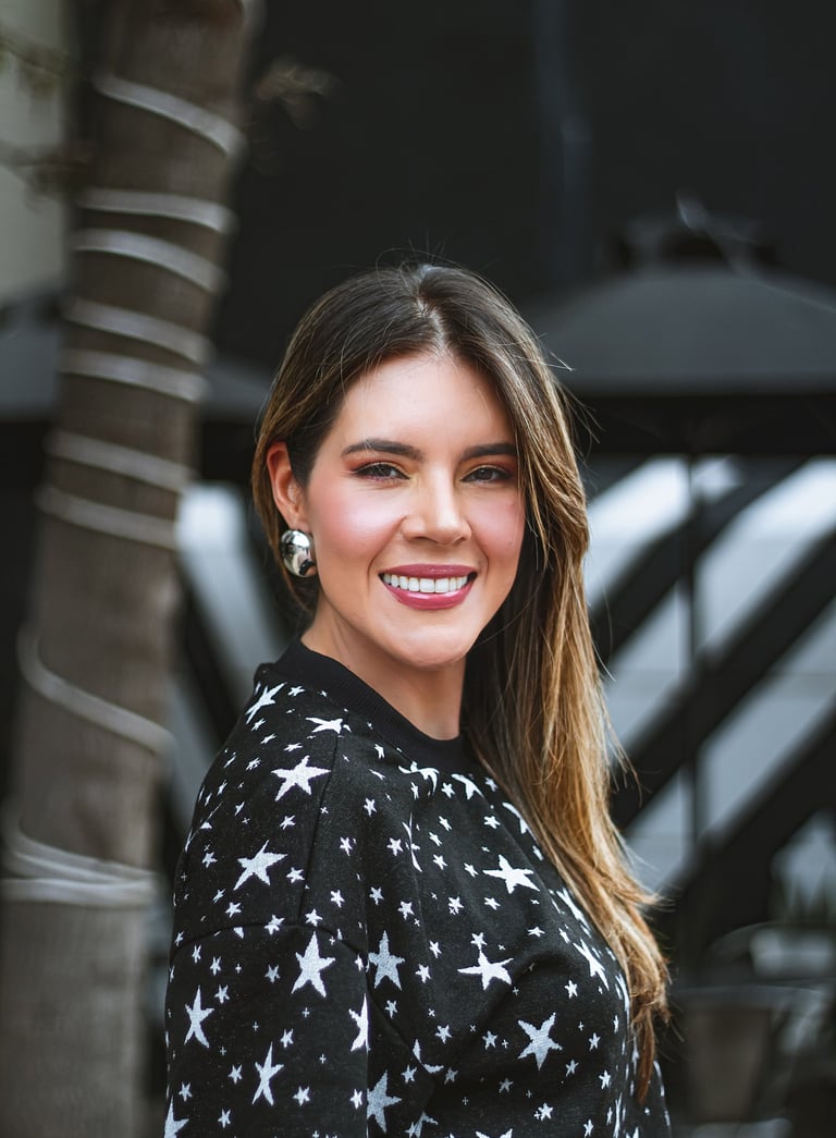 Natalia Devia sonriendo junto a una palmera, suéter negro con estrellas